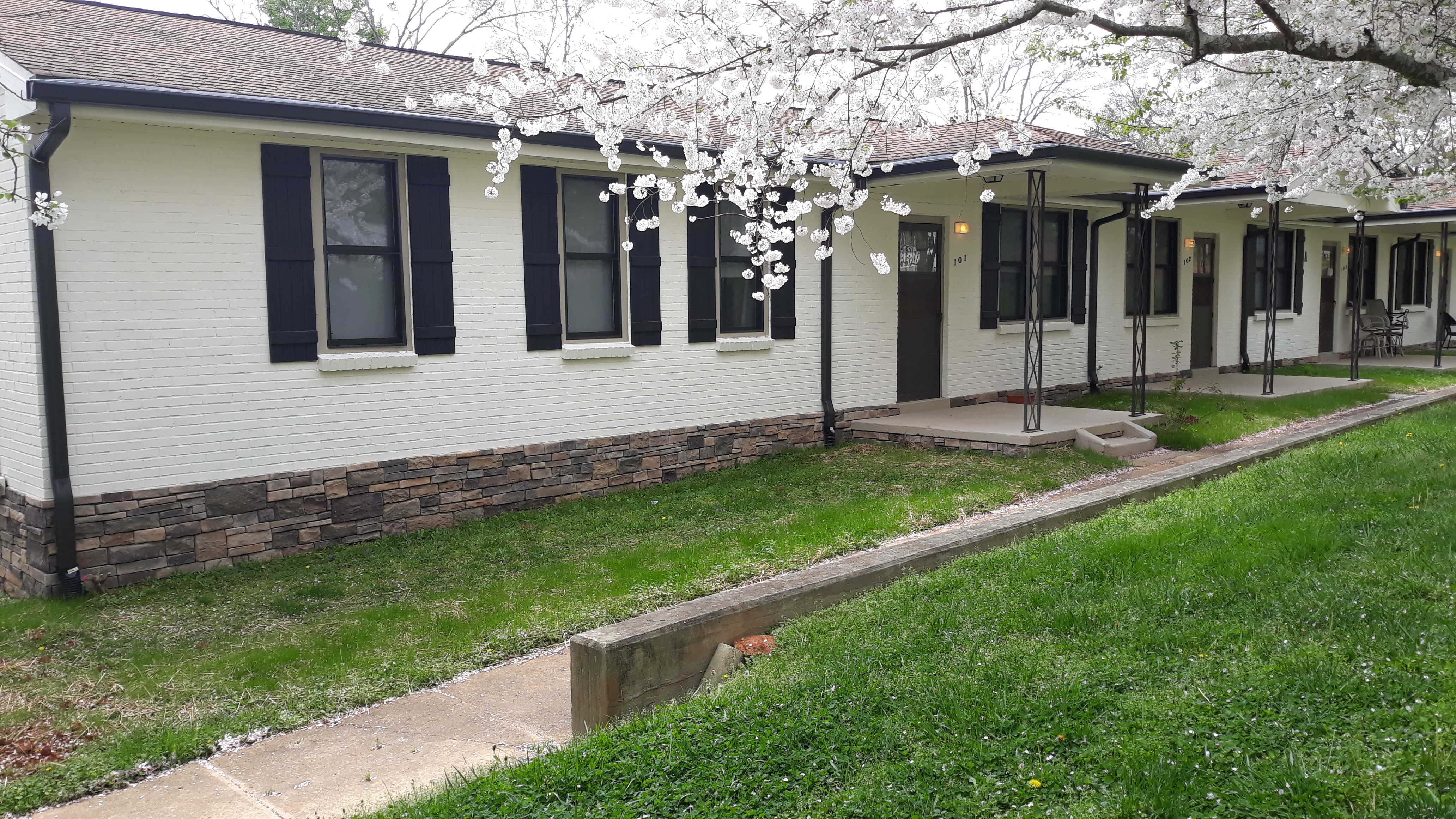 This image displays the entrances and front yard to a row house